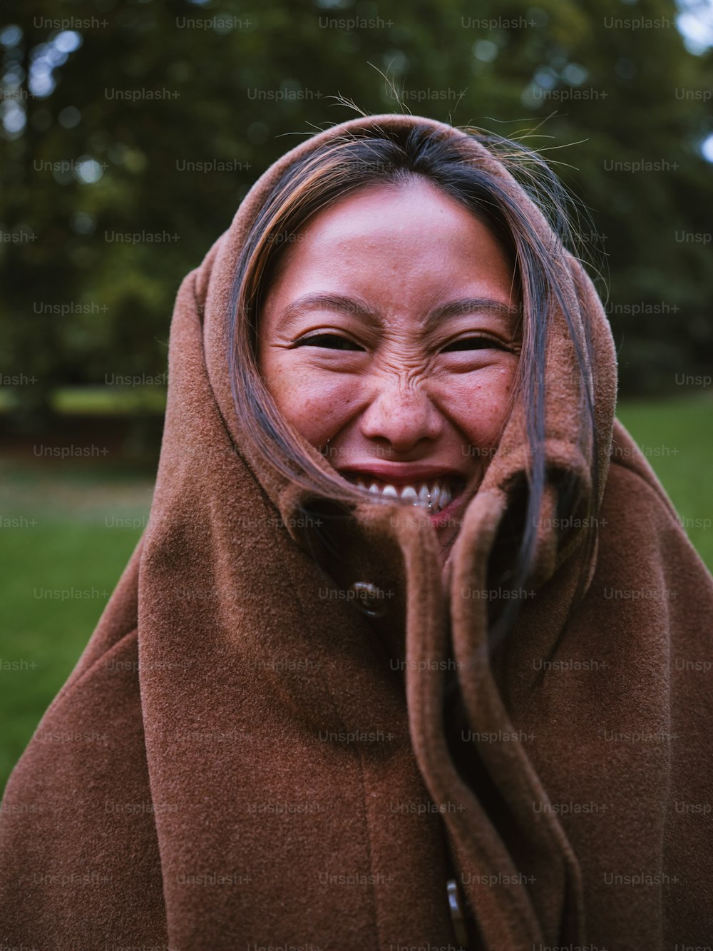 a woman wearing a brown coat and smiling