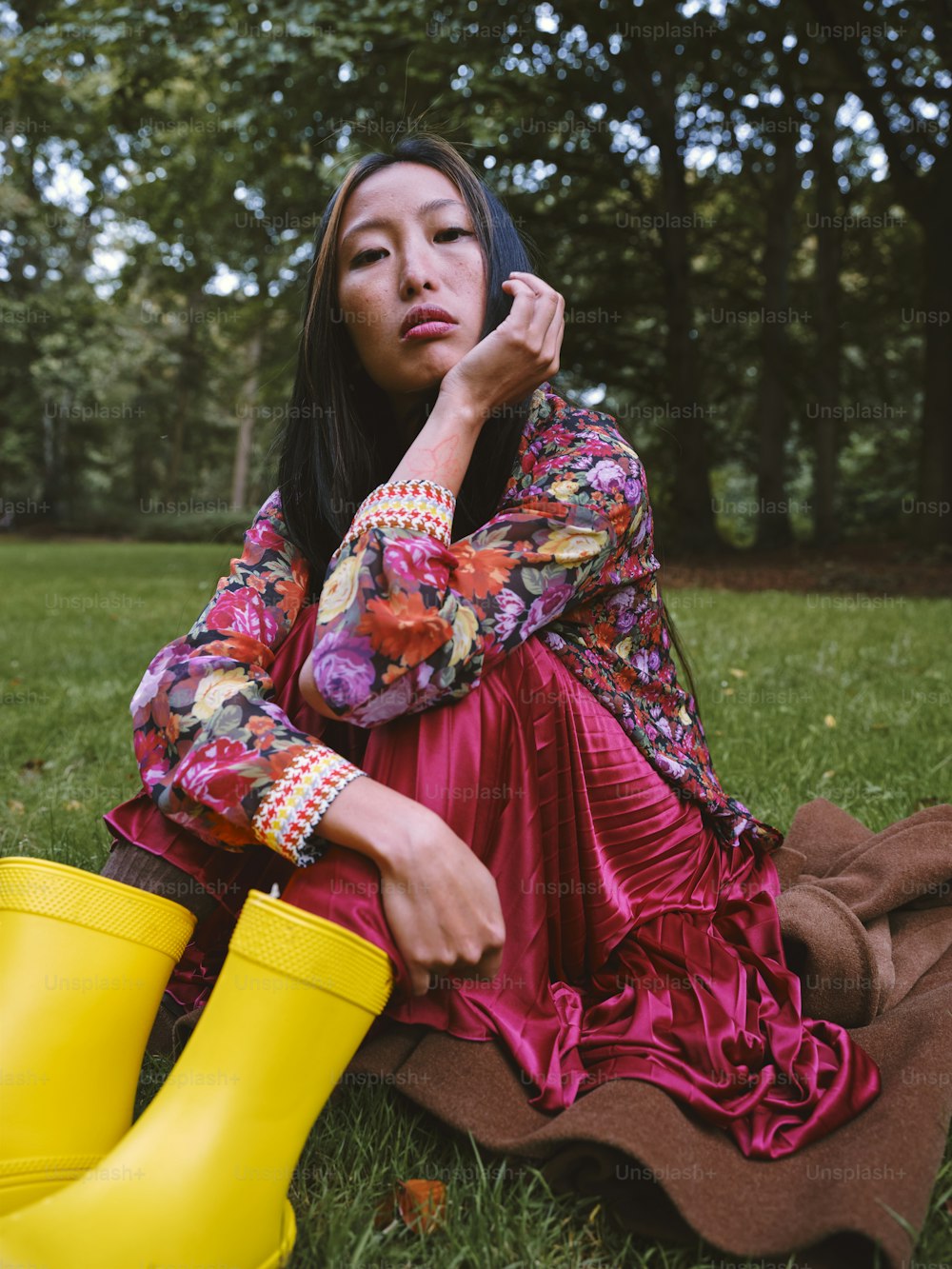 a woman sitting in the grass with a yellow rubber boot