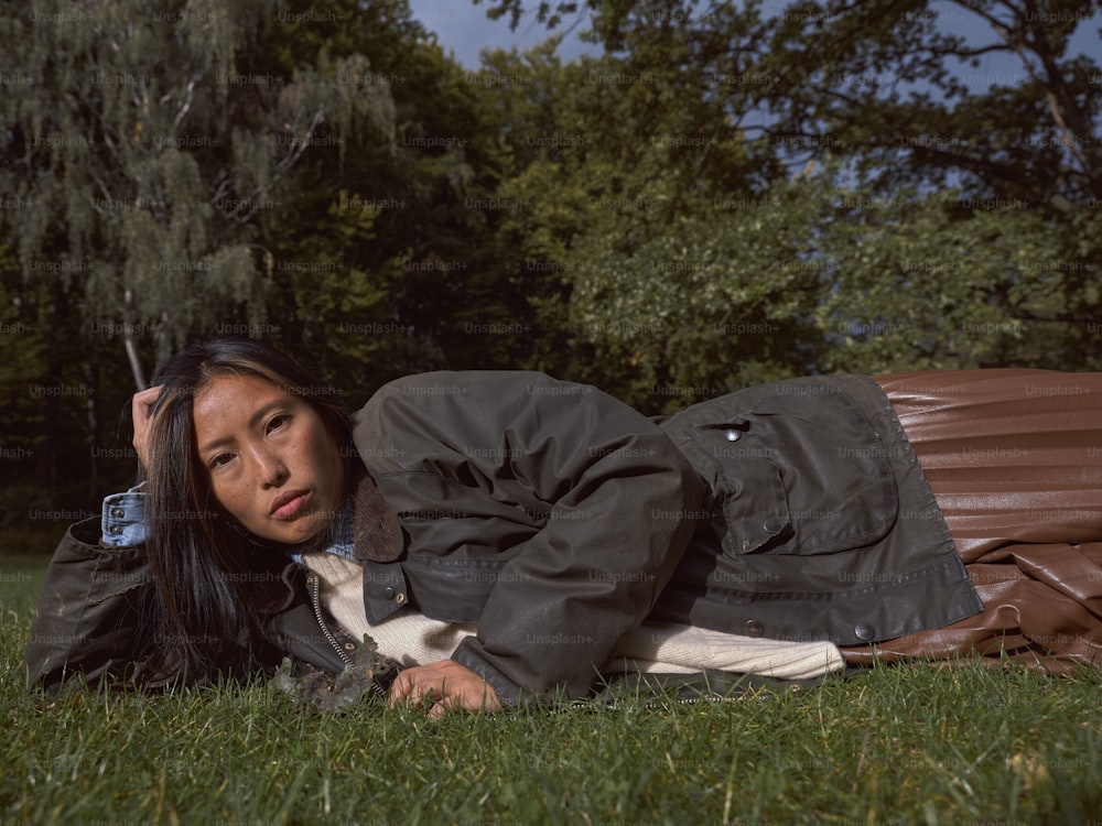 a woman laying on the grass with a cell phone in her hand
