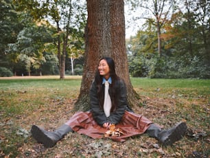 a woman sitting on the ground in front of a tree