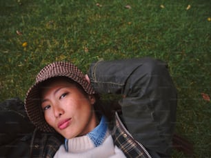 a woman laying on the ground wearing a hat