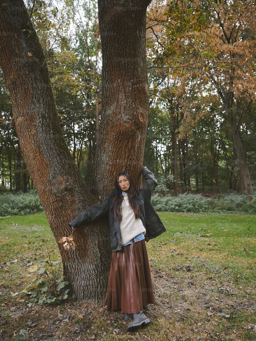 a woman leaning against a tree in a park