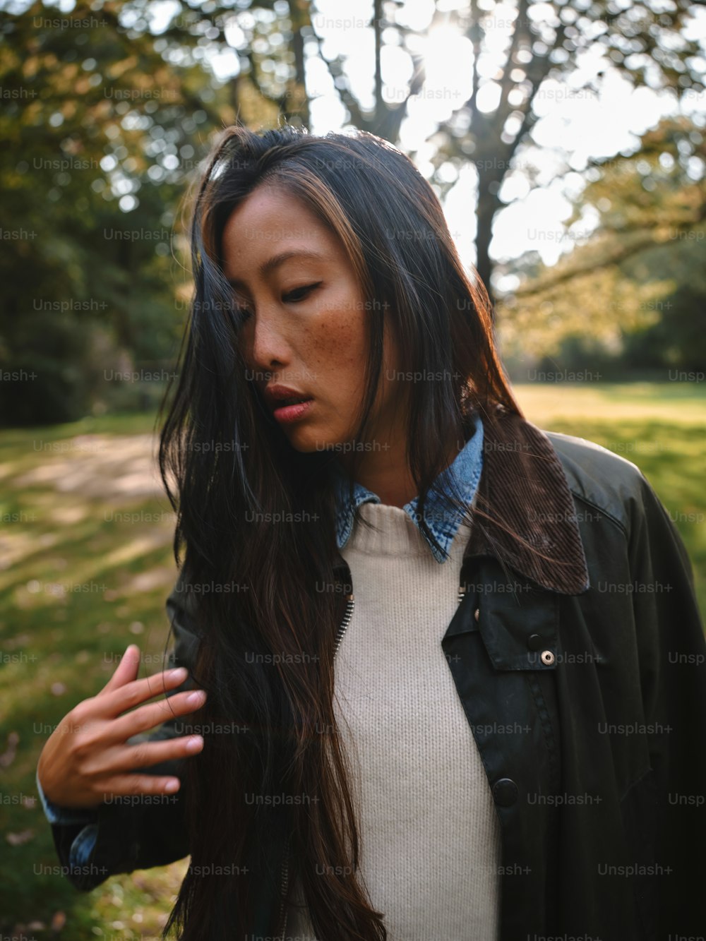 a woman with long hair standing in a park