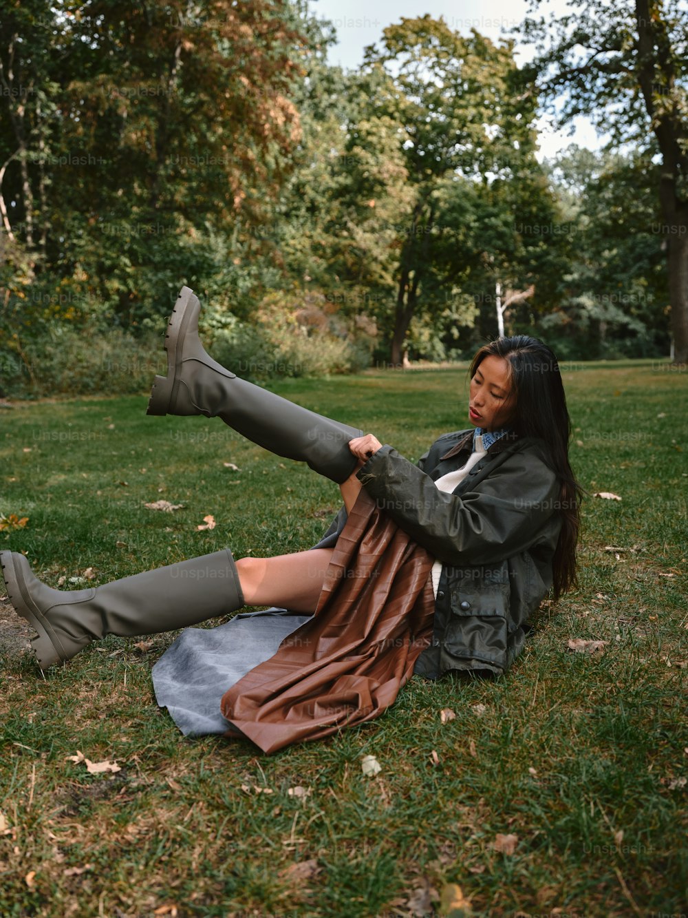 a woman sitting on the ground in a park