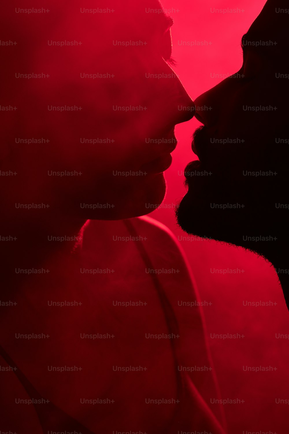 a man and a woman kissing in front of a red background