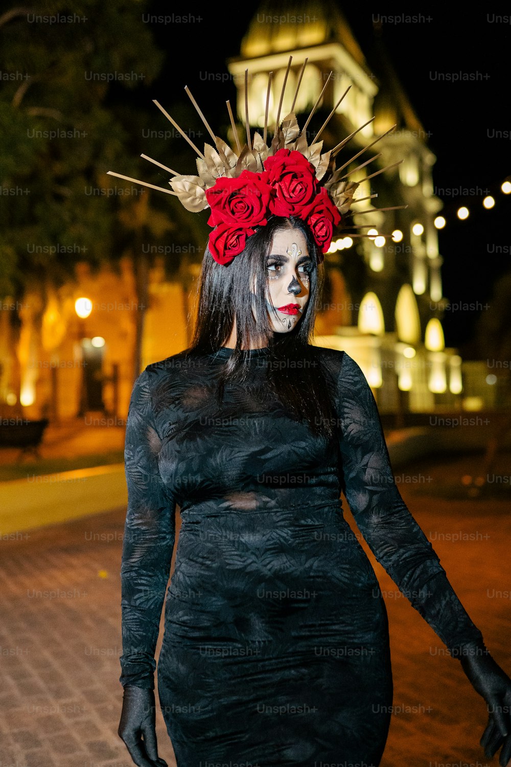 a woman in a black dress with red roses on her head