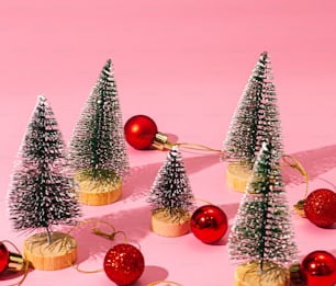 a group of small christmas trees sitting on top of a pink surface