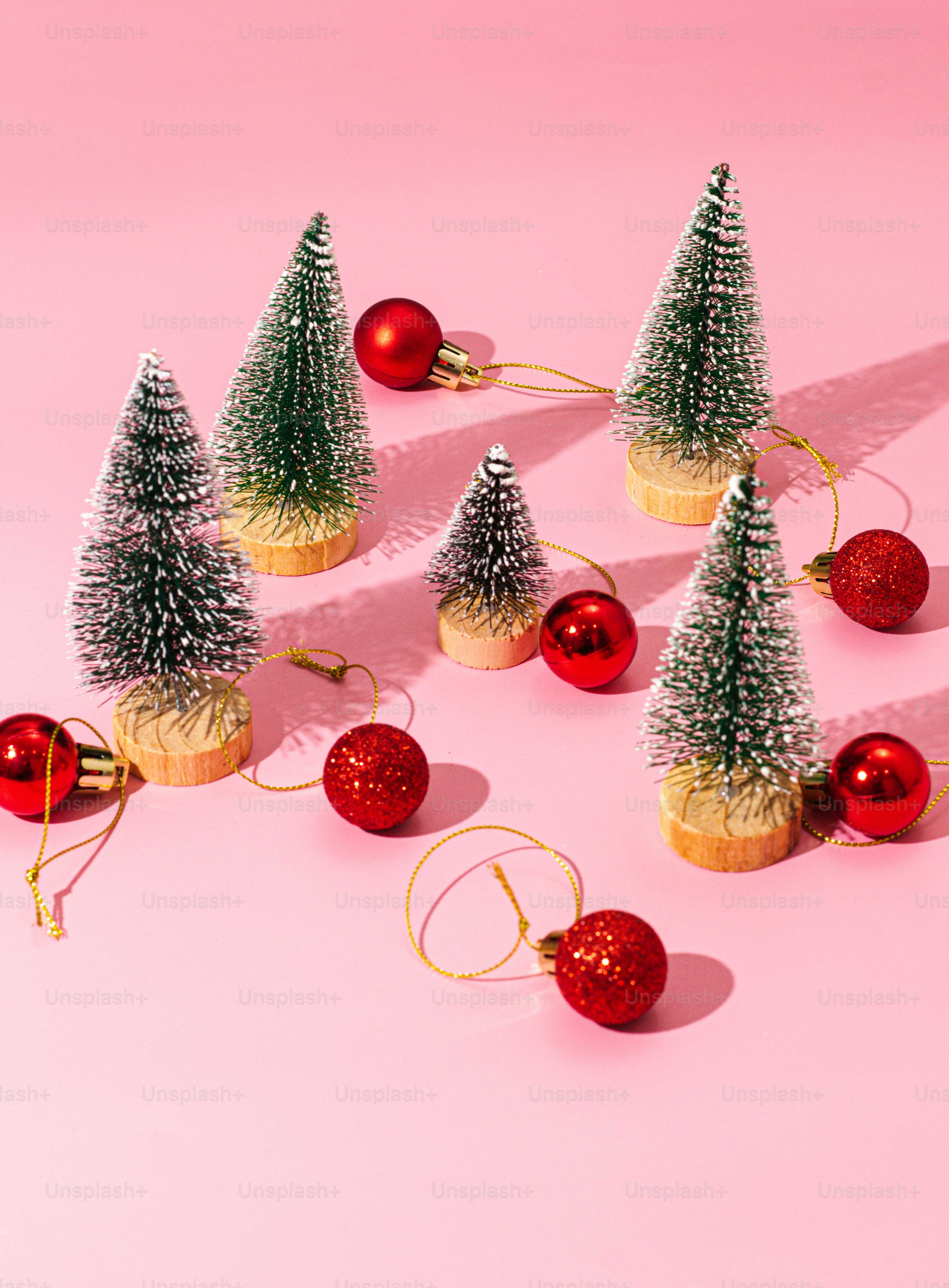 a group of small christmas trees sitting on top of a pink surface