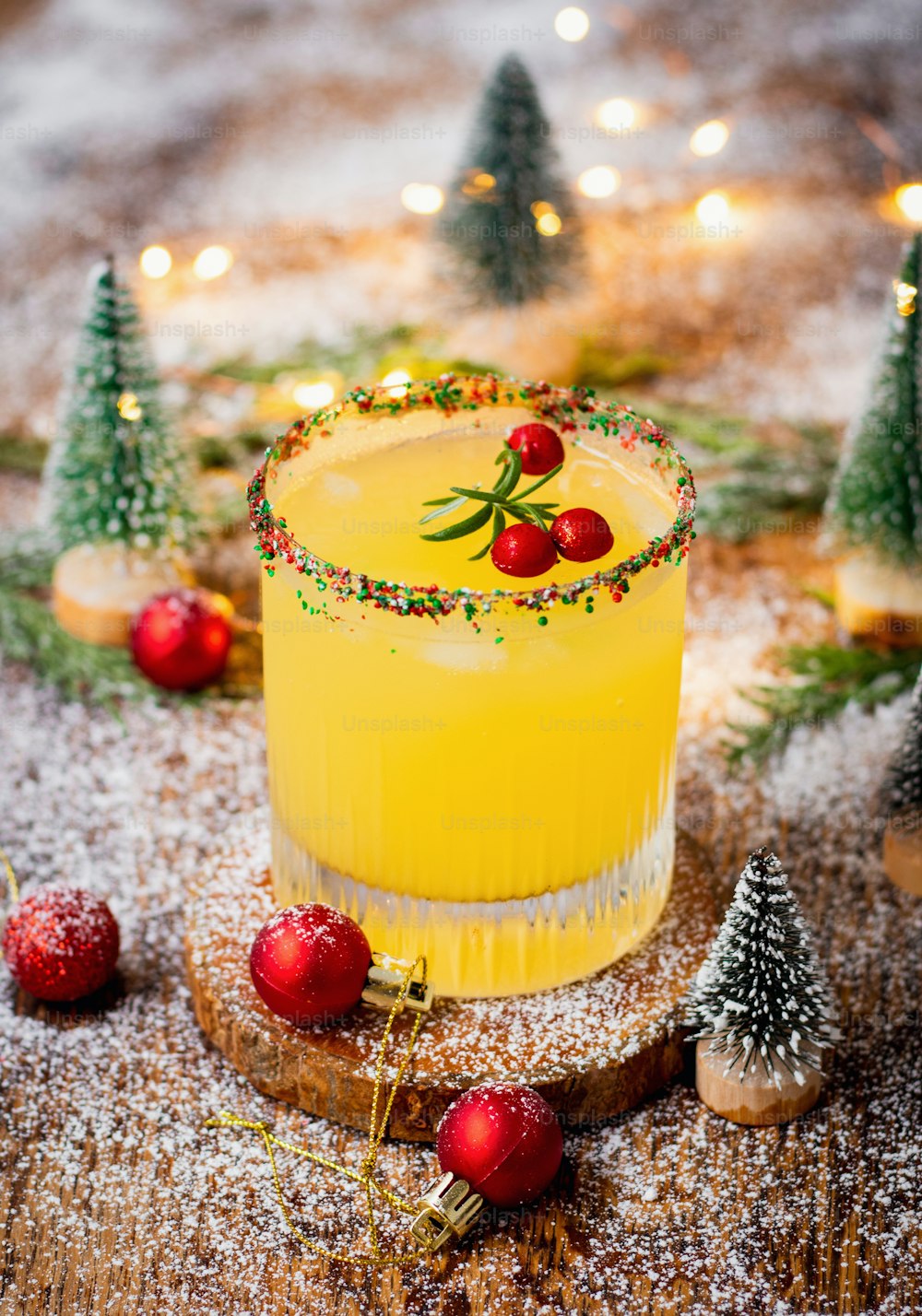 a yellow cocktail in a glass surrounded by christmas decorations