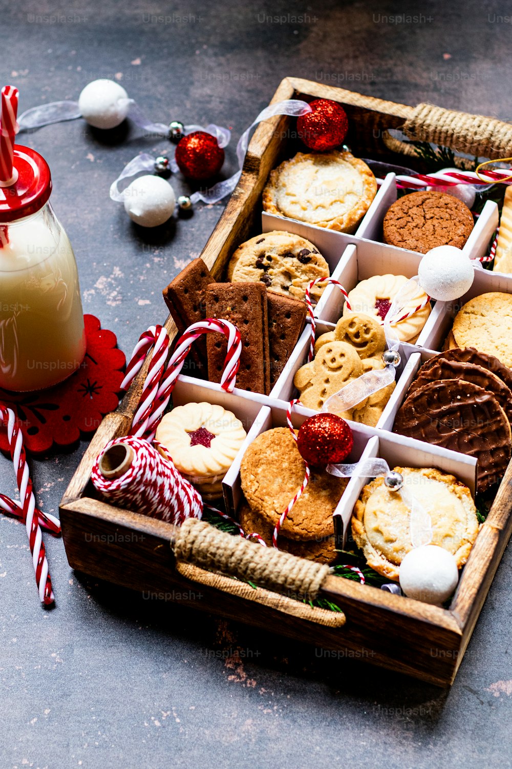 a wooden box filled with cookies next to a glass of milk