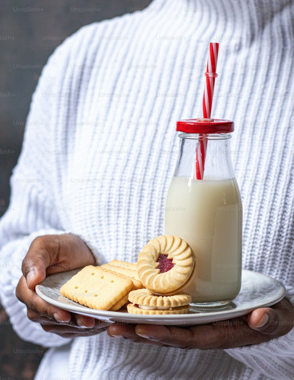 um homem segurando um prato de biscoitos e um copo de leite