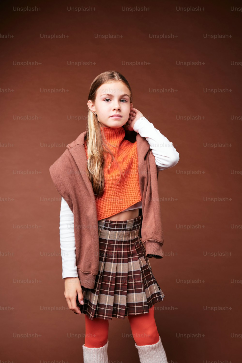 a girl in a skirt and sweater posing for a picture