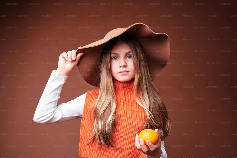 a woman in a hat holding an apple