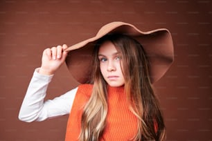 una mujer con un sombrero marrón y un suéter naranja
