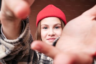a young girl wearing a red beanie is making a hand gesture