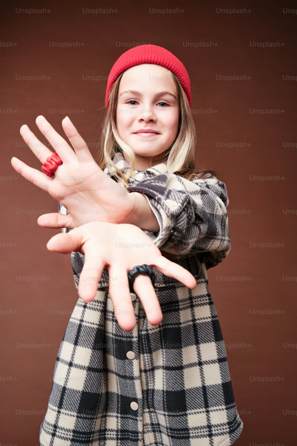 a young girl wearing a red beanie holding her hands out