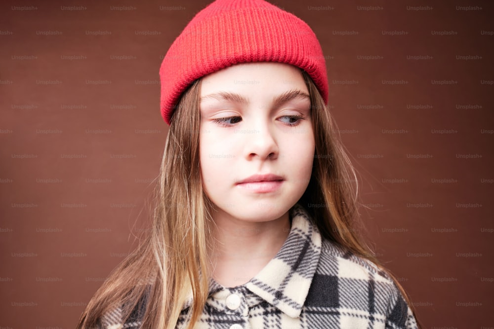 a young girl wearing a red hat and a plaid coat