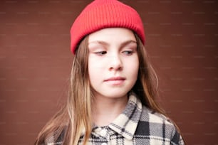 a young girl wearing a red hat and a plaid coat