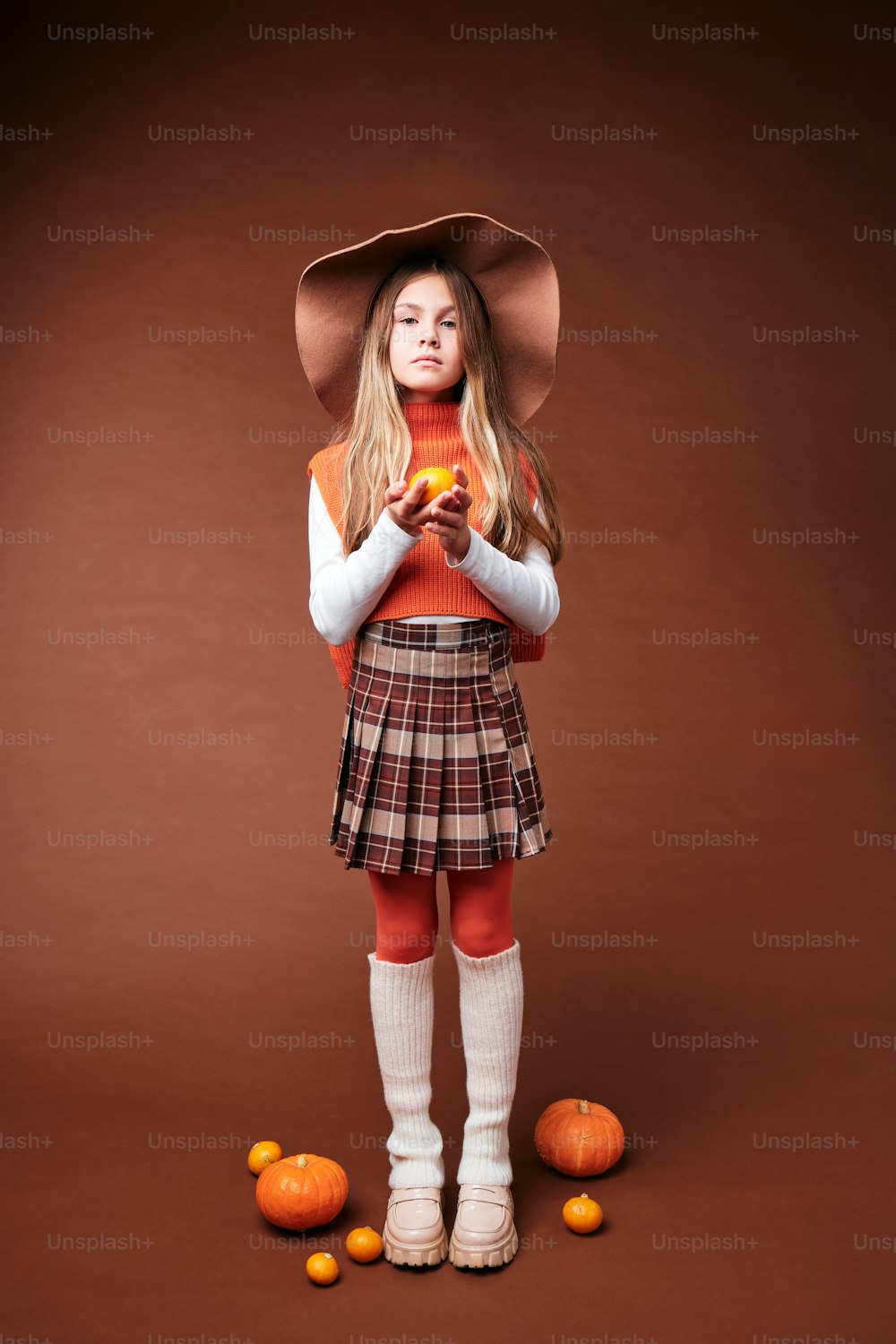 a young girl wearing a hat and a plaid skirt