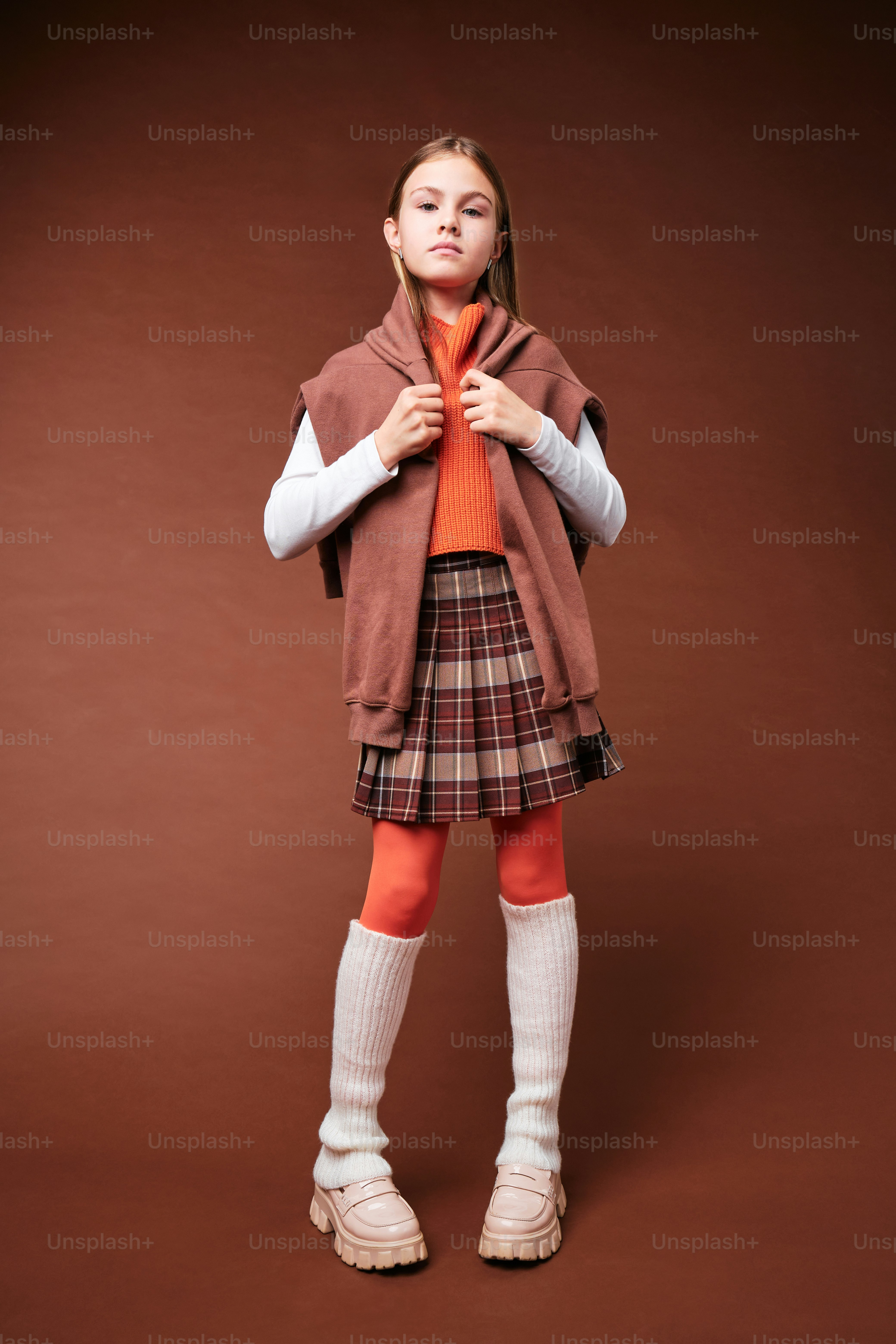 A girl in autumn clothes on studio background in warm color scheme