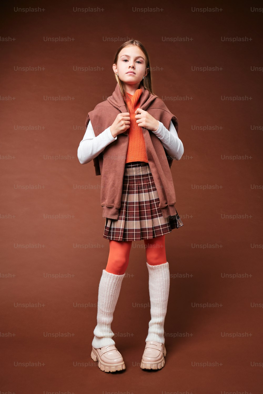 a young girl in a skirt and jacket posing for a picture