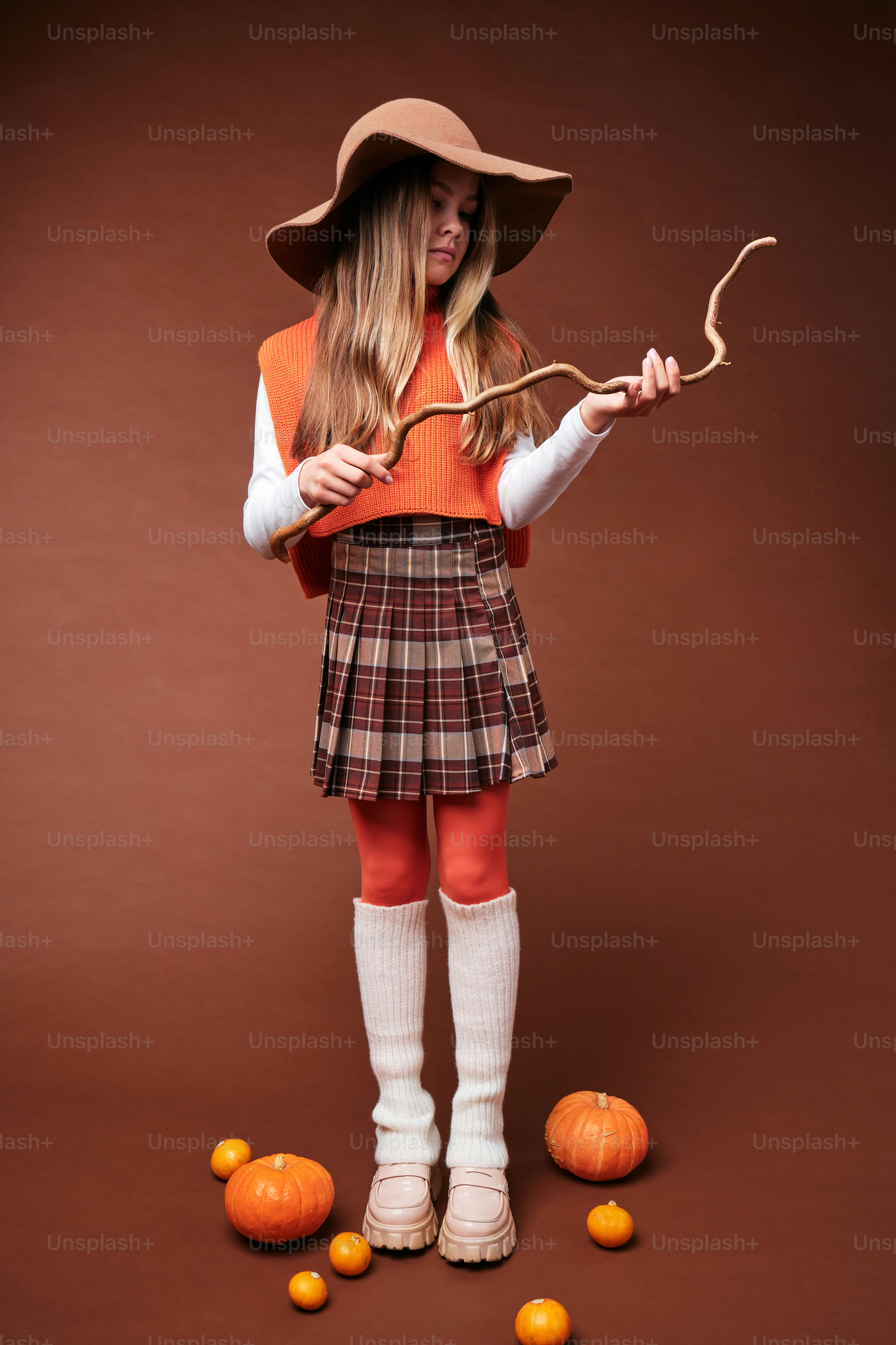 a woman in a plaid skirt holding a stick and oranges