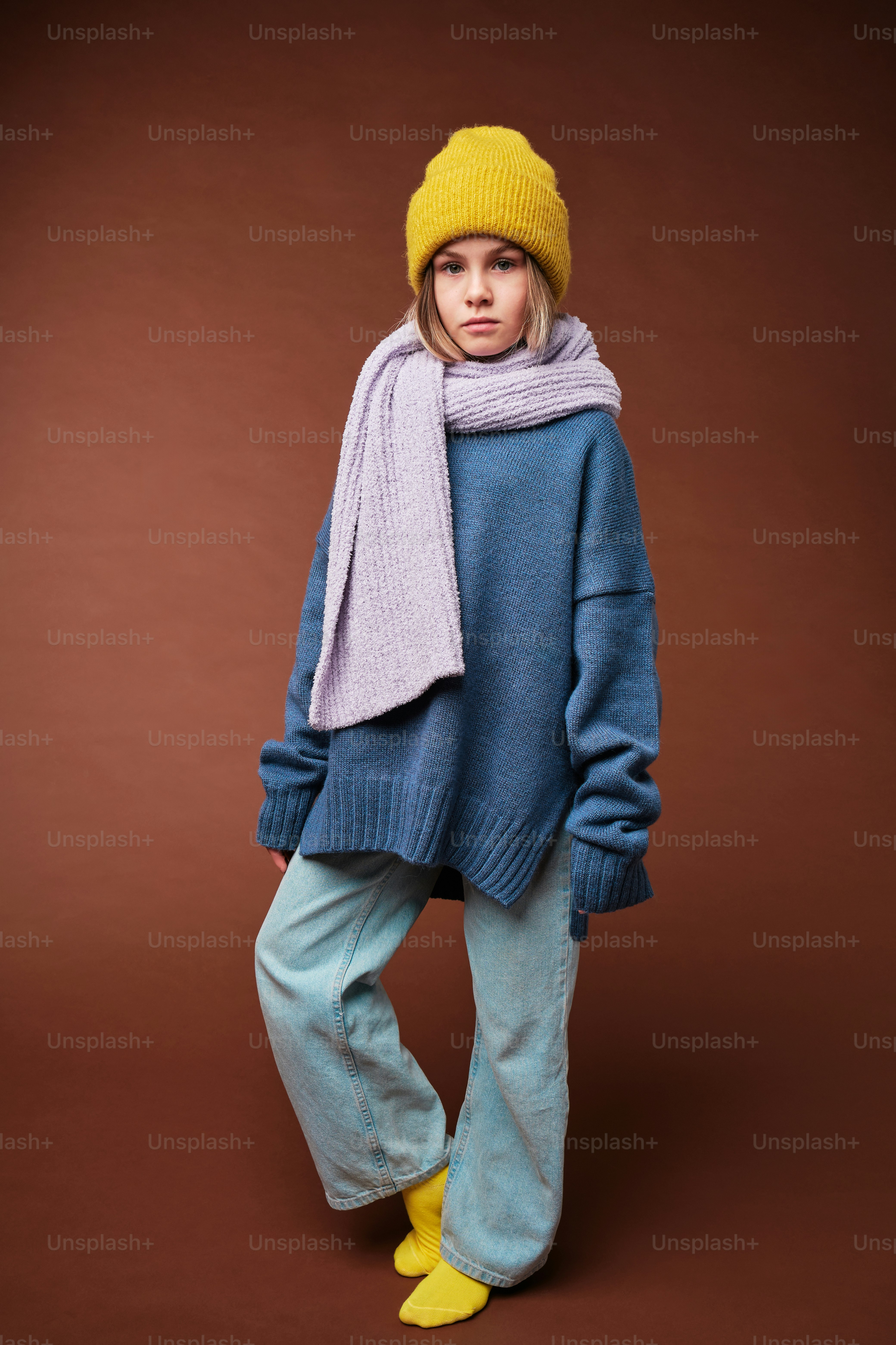 a young girl wearing a blue sweater and yellow boots