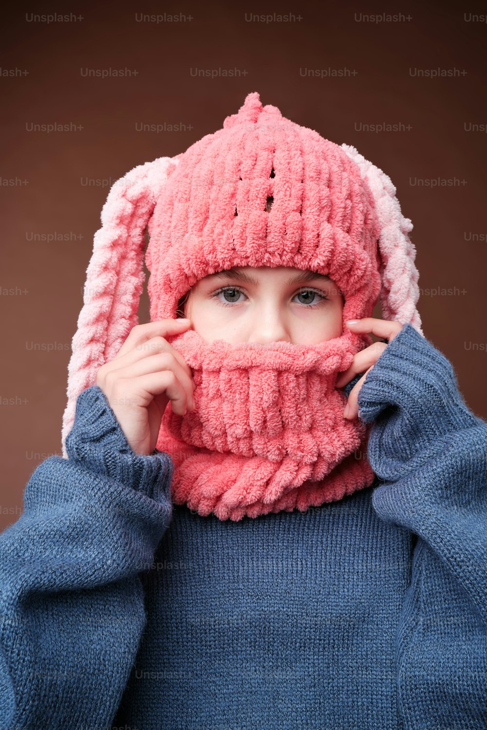 a young girl wearing a pink knitted hat and scarf