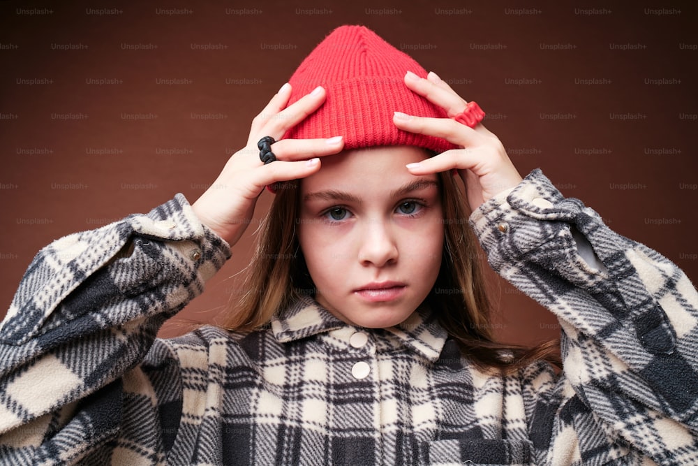 une jeune fille tenant un chapeau rouge au-dessus de sa tête
