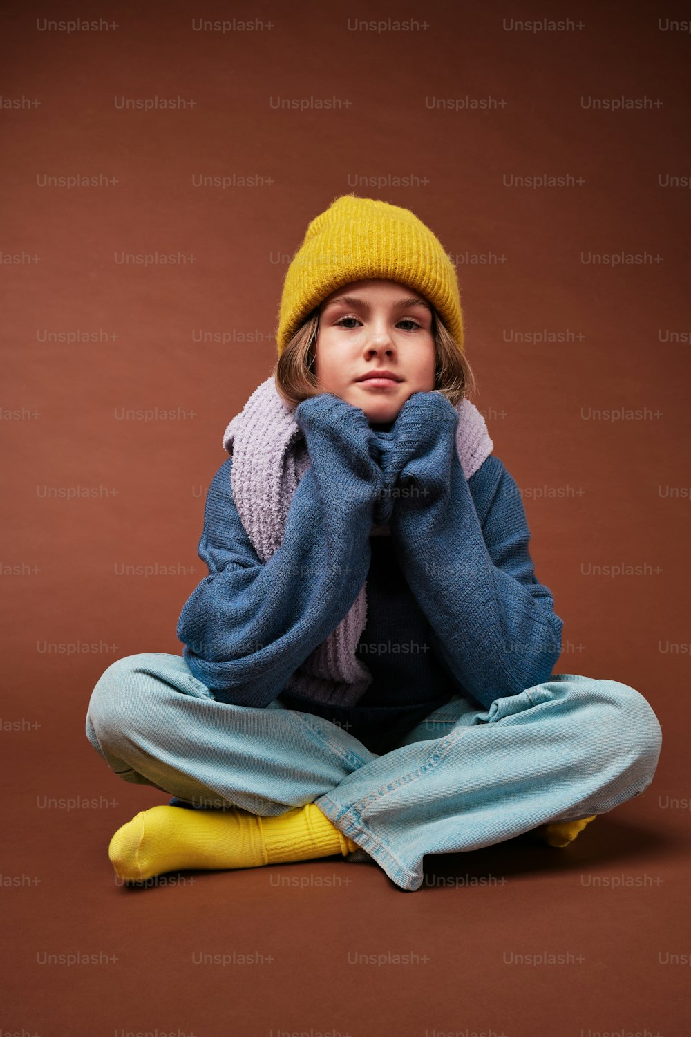 a little girl sitting on the floor wearing a yellow hat