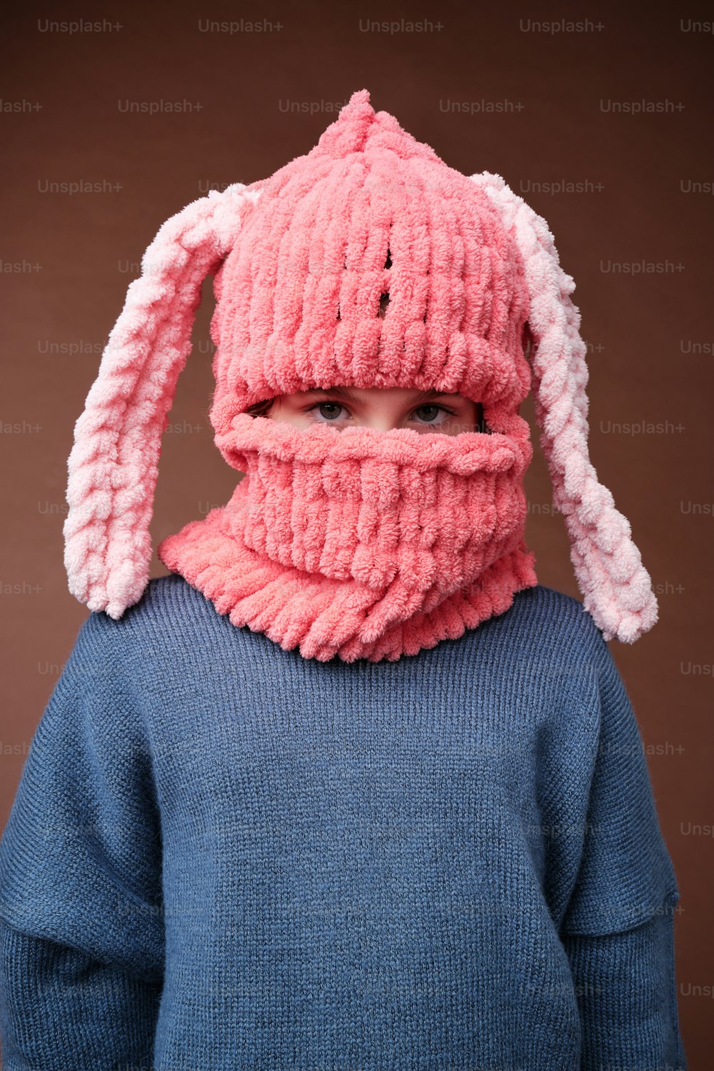 a young child wearing a knitted bunny hat and scarf