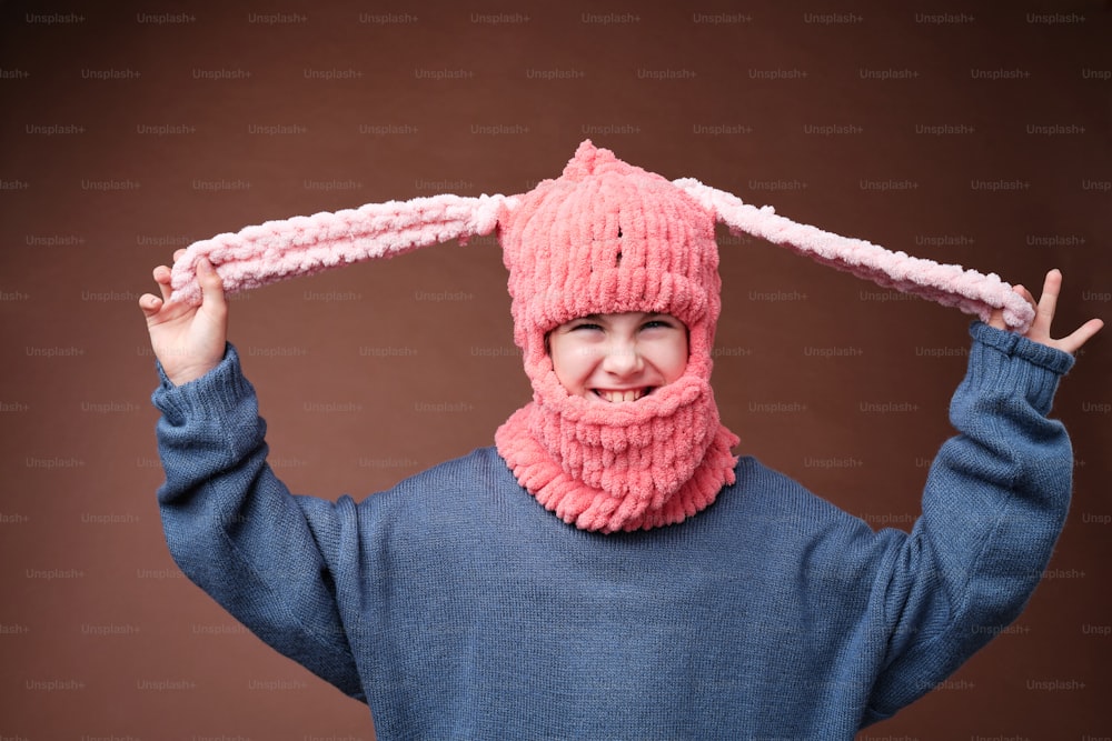 un giovane ragazzo che indossa un cappello rosa e una sciarpa