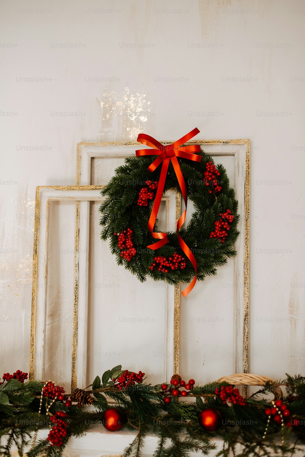 a christmas wreath on a mantle with a red bow