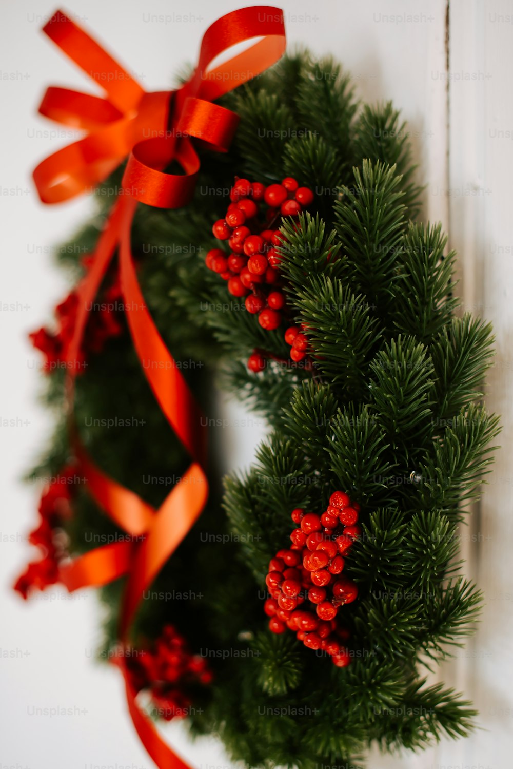 a green wreath with red berries and a red ribbon