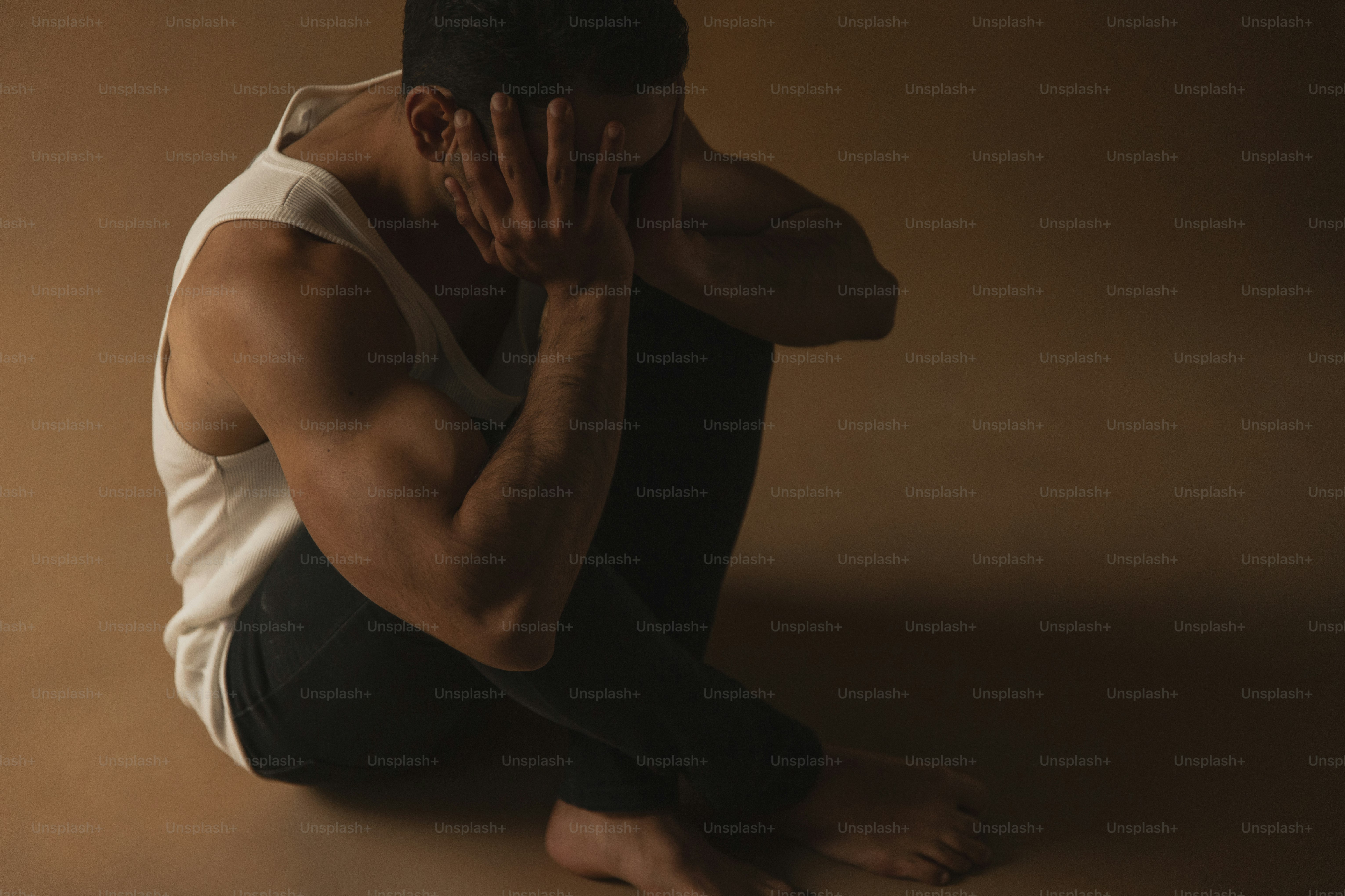 a man sitting on the ground with his hands to his face