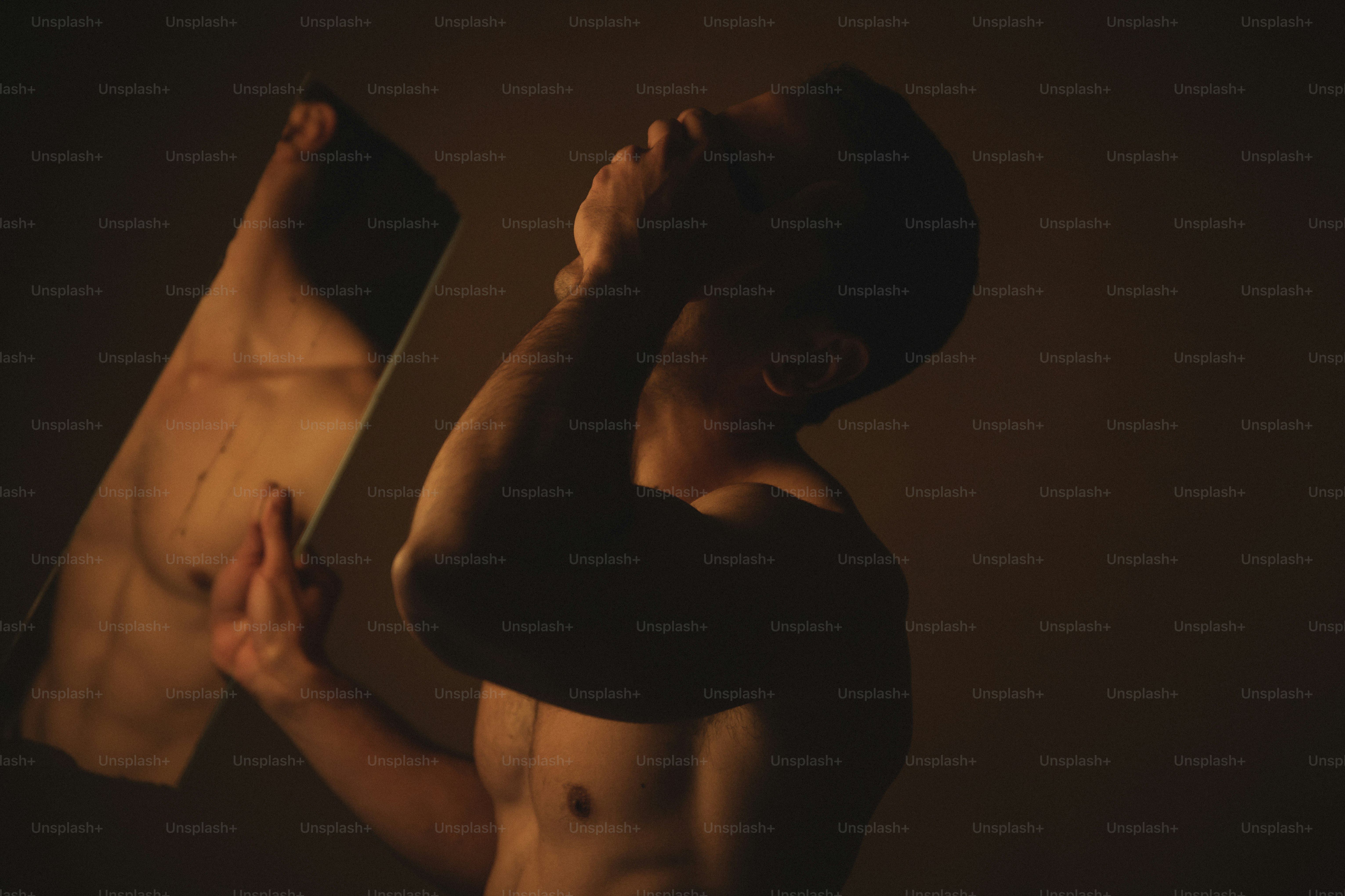 a shirtless man holding a mirror in his hands