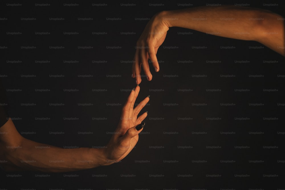 duas mãos se aproximando uma da outra no escuro