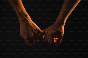 two hands holding each other in the dark