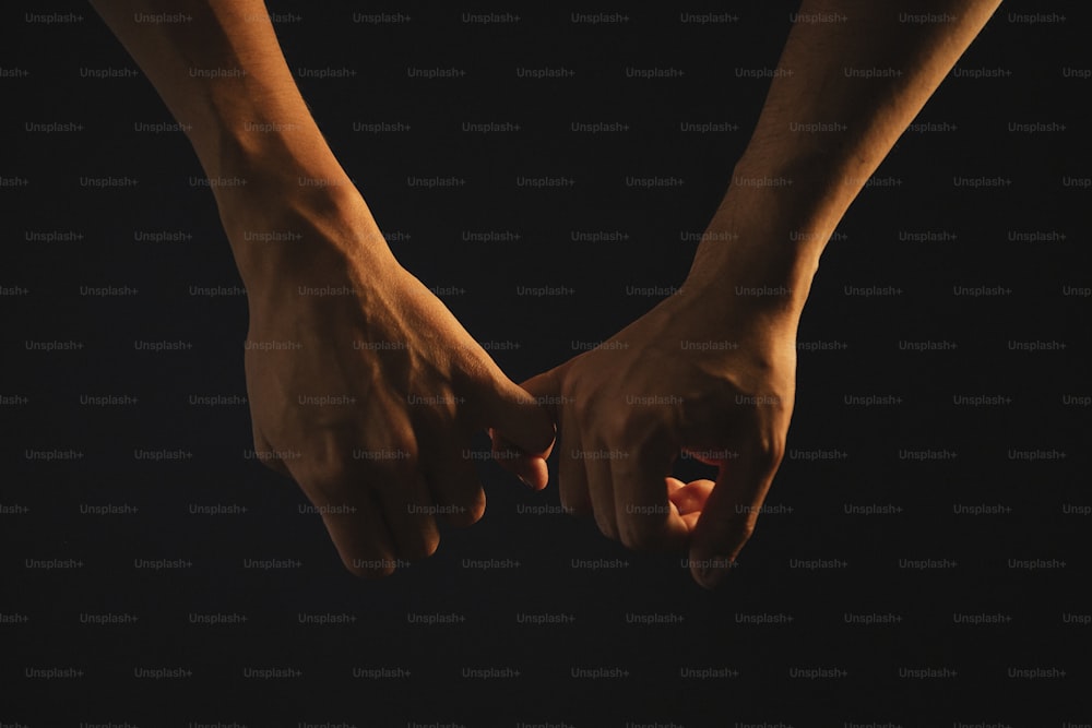 Dos manos que se sostienen en la oscuridad