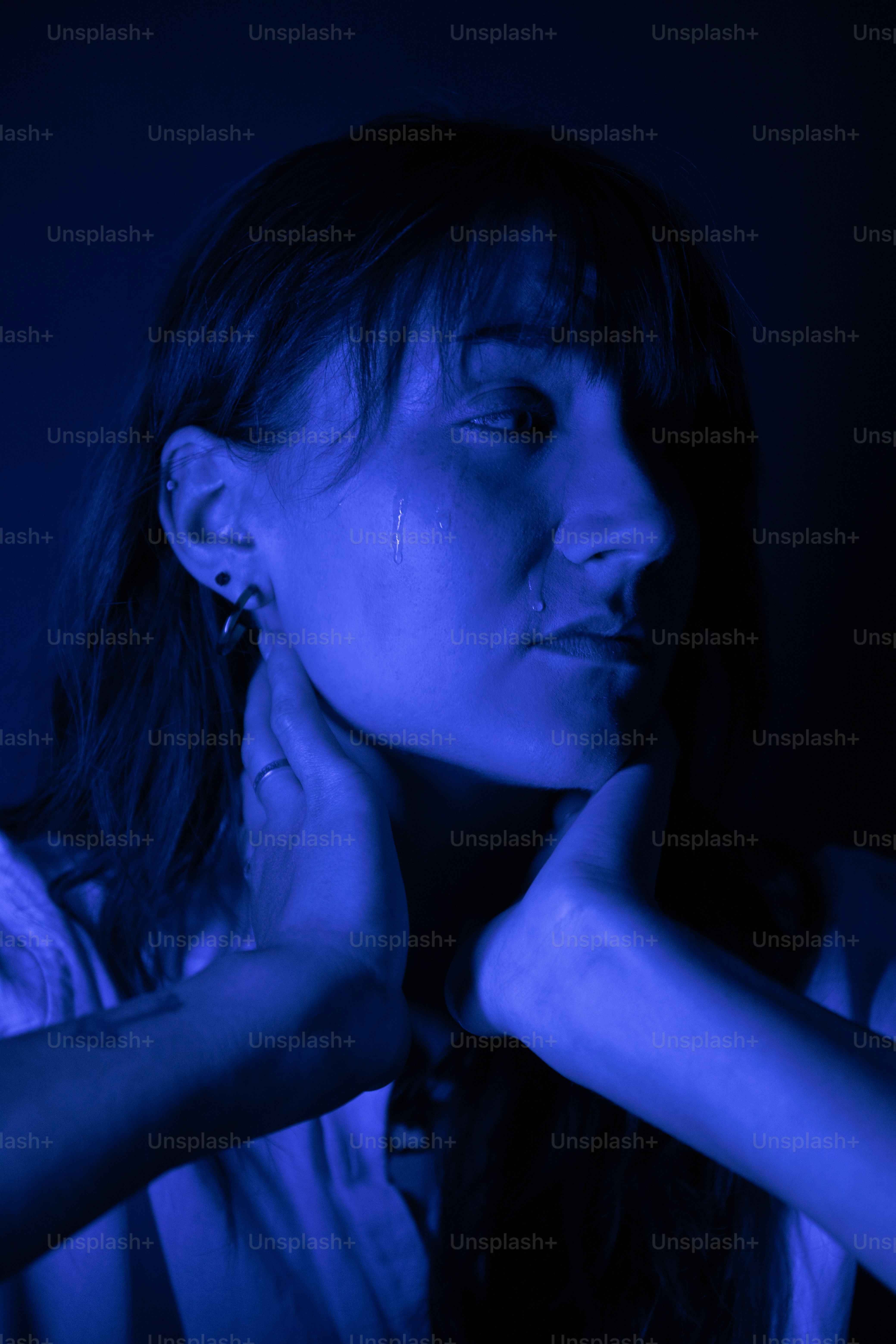 a woman in a white shirt is holding her hand near her face