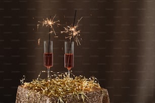 two champagne flutes with sparklers on top of a cake