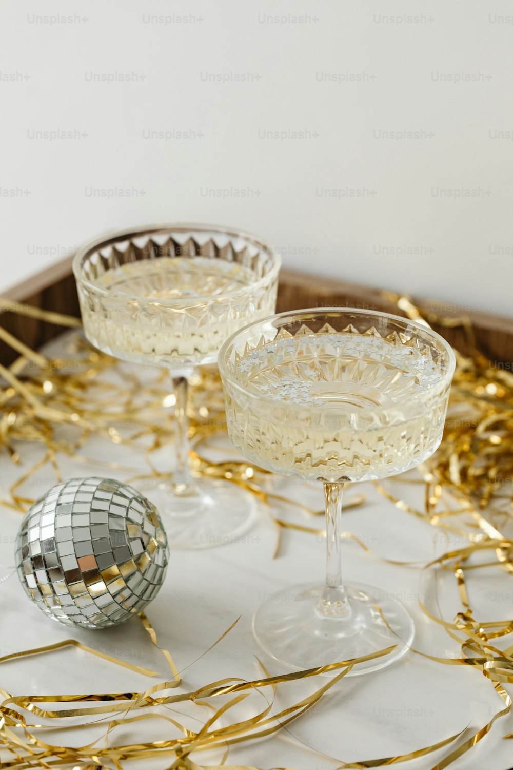two glasses of champagne on a tray with gold streamers