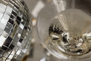 um close up de uma taça de vinho com uma bola de discoteca ao fundo