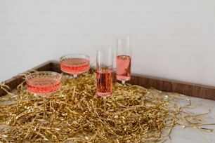 three glasses of wine on a tray with gold tinsel