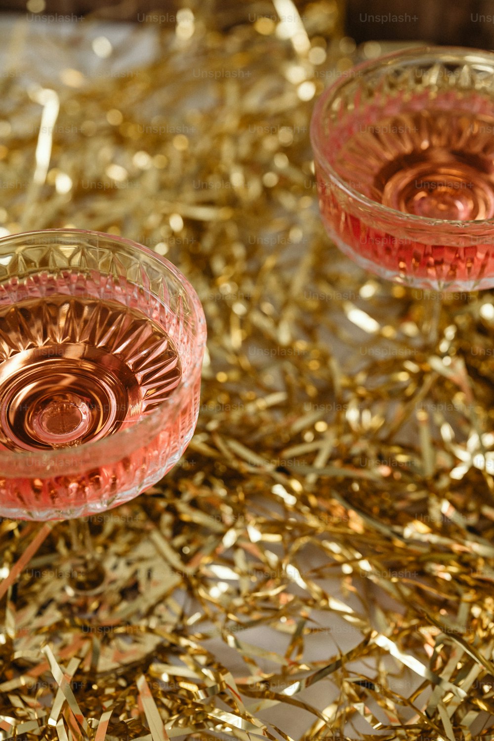 two wine glasses sitting on top of a pile of gold tinsel