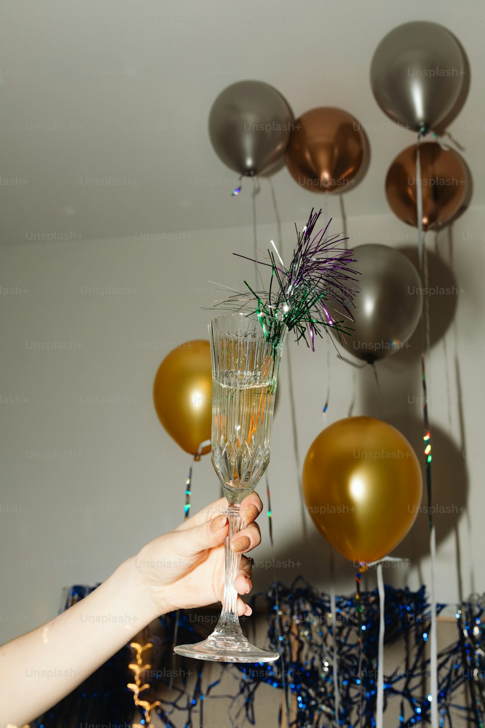 a person holding a wine glass with a bunch of balloons behind it