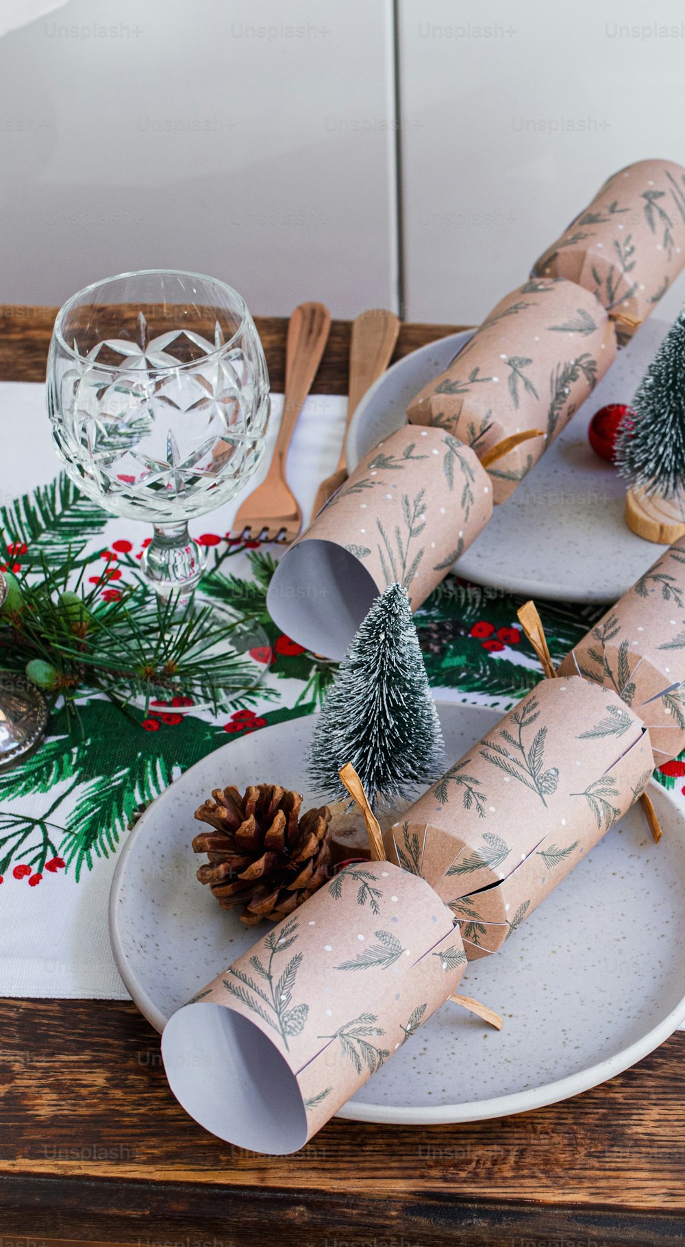 a christmas table setting with rolled up wrapping and pine cones