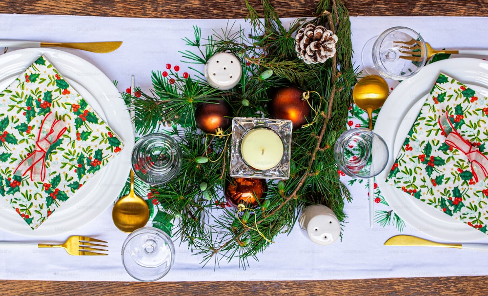 a christmas table setting with pine cones, candles and ornaments