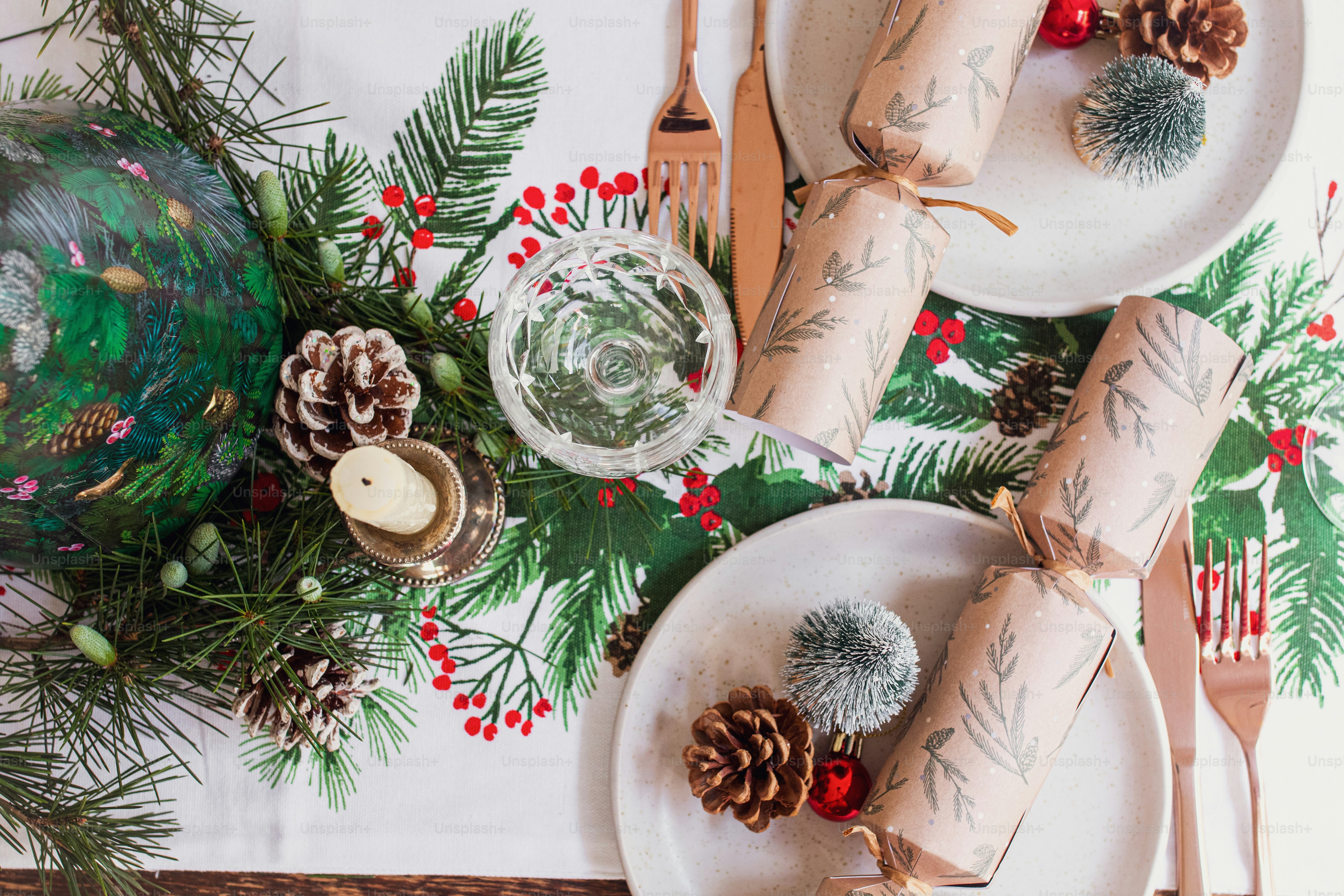 a christmas table setting with pine cones, candles and napkins