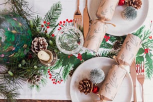 a christmas table setting with pine cones, candles and napkins